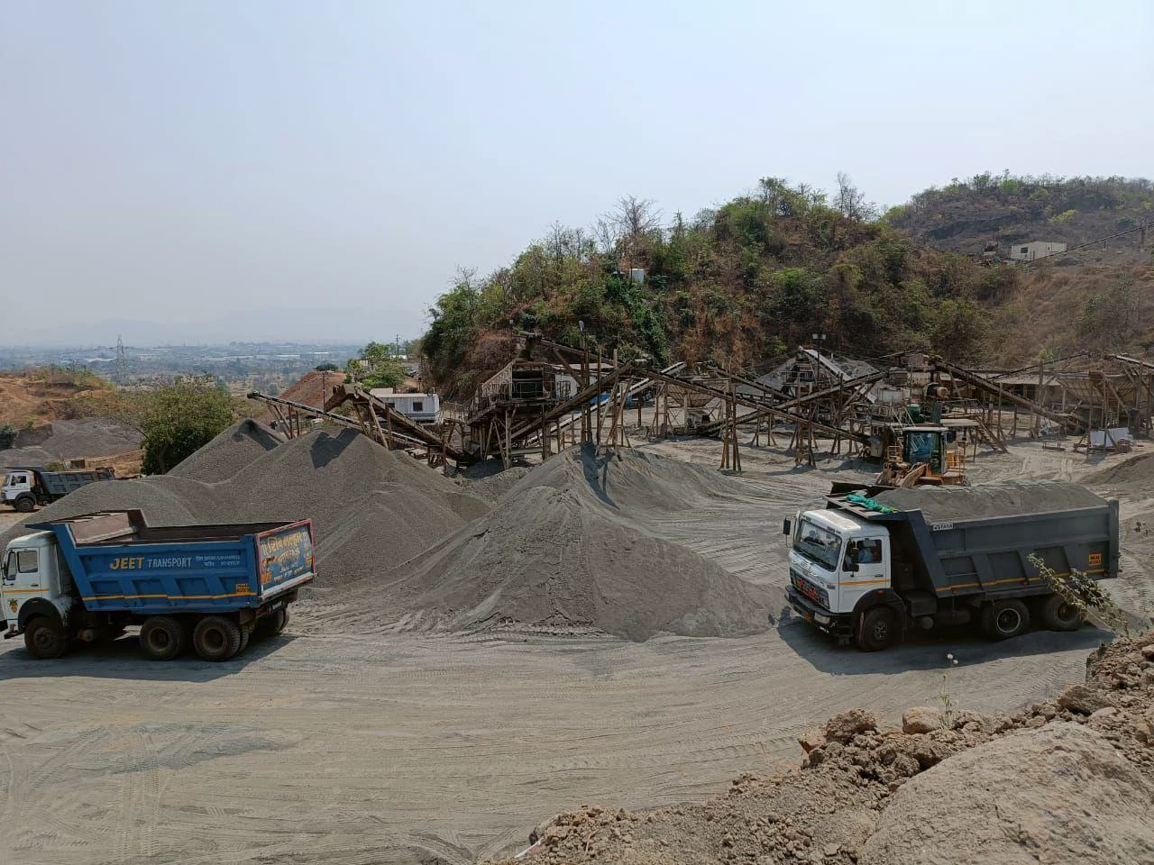 Tippers loading from the black basalt stockyard